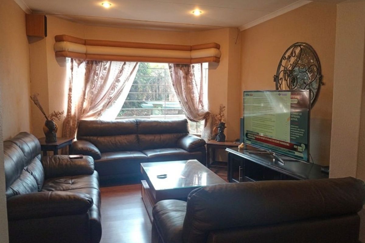 A comfortable living room featuring a bay window, recessed downlighting, and laminate flooring, providing a functional and inviting space for relaxation.