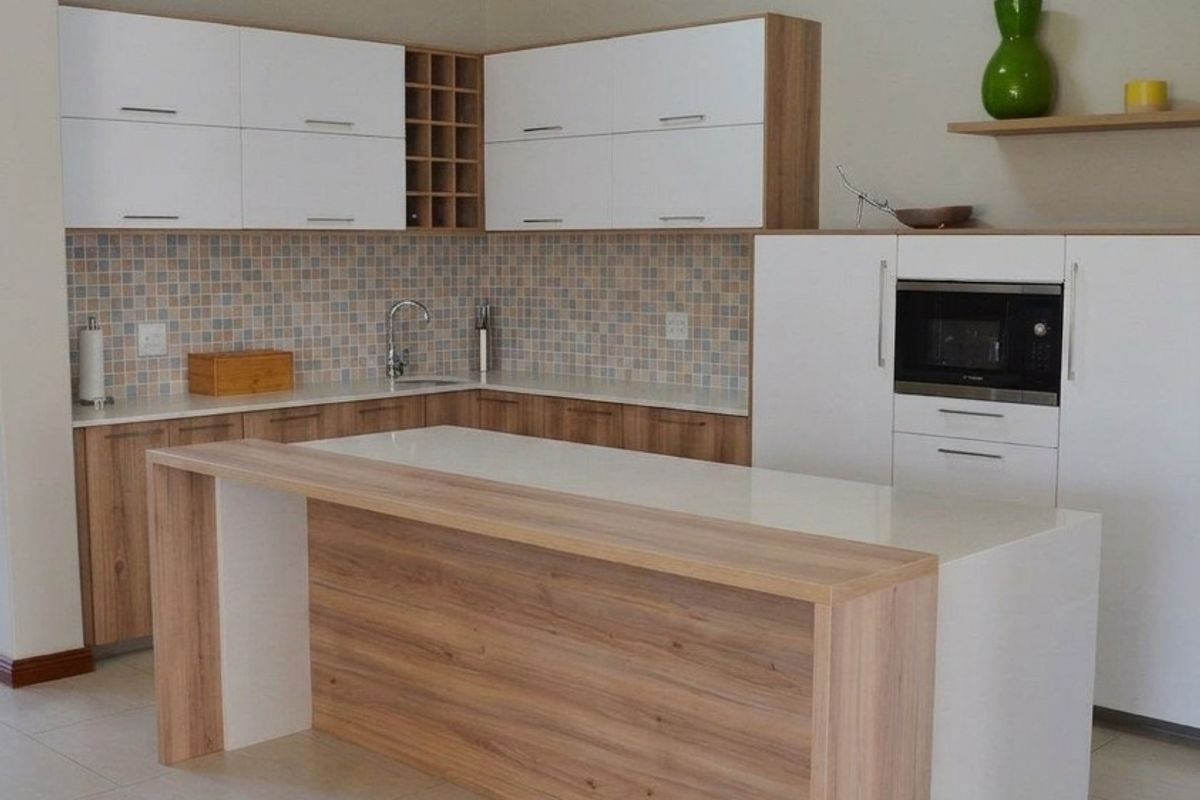 Modern kitchen featuring two-tone cabinetry, a central island with stone countertop, mosaic tile backsplash, and integrated microwave.