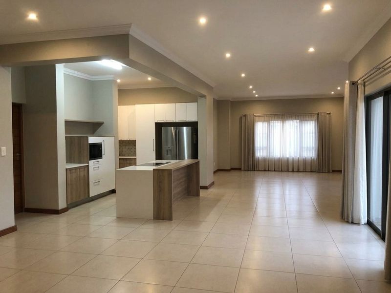Spacious open-plan living and kitchen area featuring modern cabinetry, a central island, tiled floors, and large sliding doors leading to the exterior.