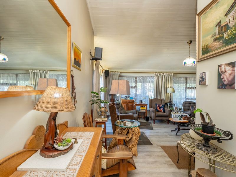A comfortable living room featuring timber-look flooring, a high tongue and groove ceiling, and large sliding glass doors that provide natural light.