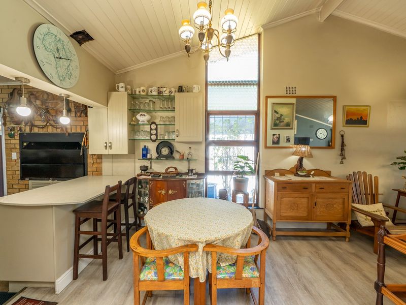 Open-plan living and dining area featuring a vaulted ceiling, built-in fireplace with brick surround, and a breakfast bar with integrated cabinetry.