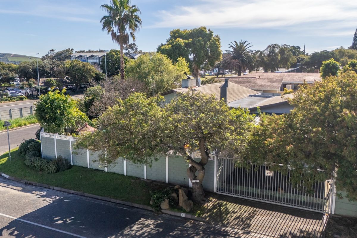 Aerial view of the property showing the street-facing perimeter wall, metal gate, and roof structure within a suburban neighborhood setting.