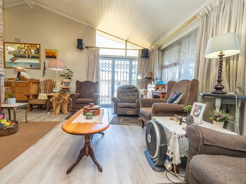 Spacious living room featuring a brick fireplace, vaulted ceilings, and laminate flooring, with direct access to the outdoor area through a sliding glass door.
