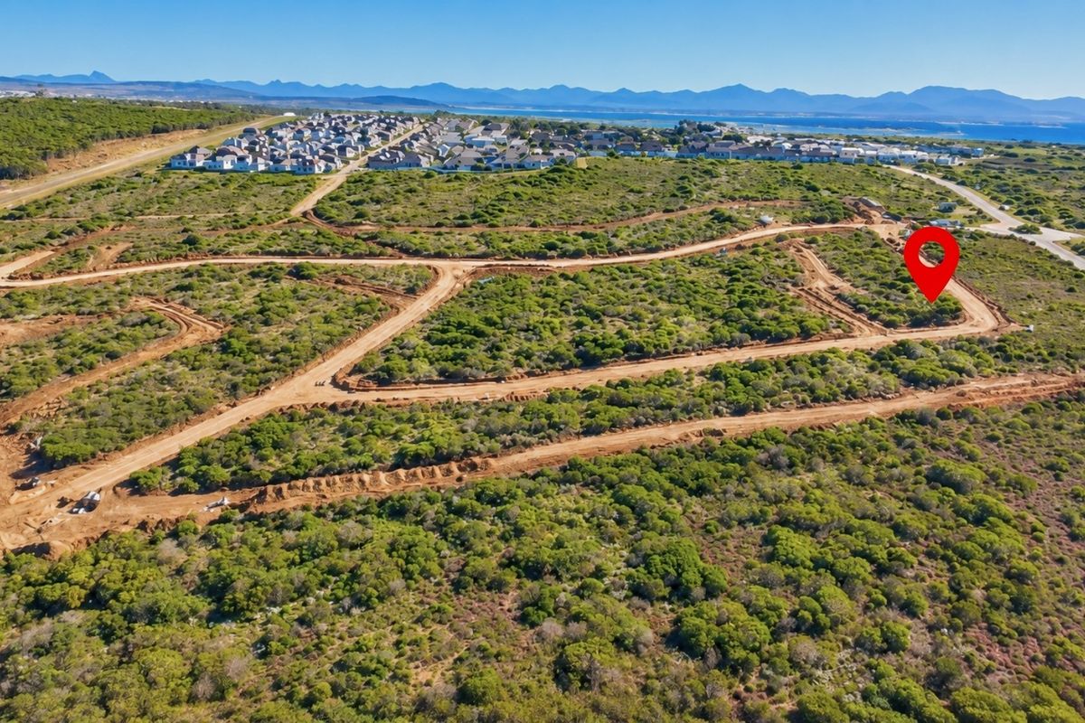 Aerial view of a vacant residential plot within a developing estate, featuring natural coastal vegetation and established access roads.