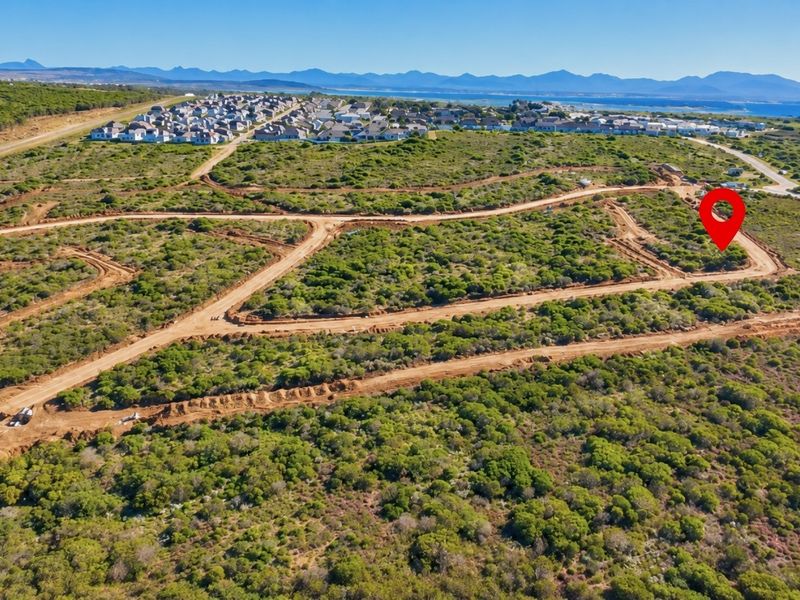 Aerial view of a vacant residential plot within a developing estate, featuring natural coastal vegetation and established access roads.
