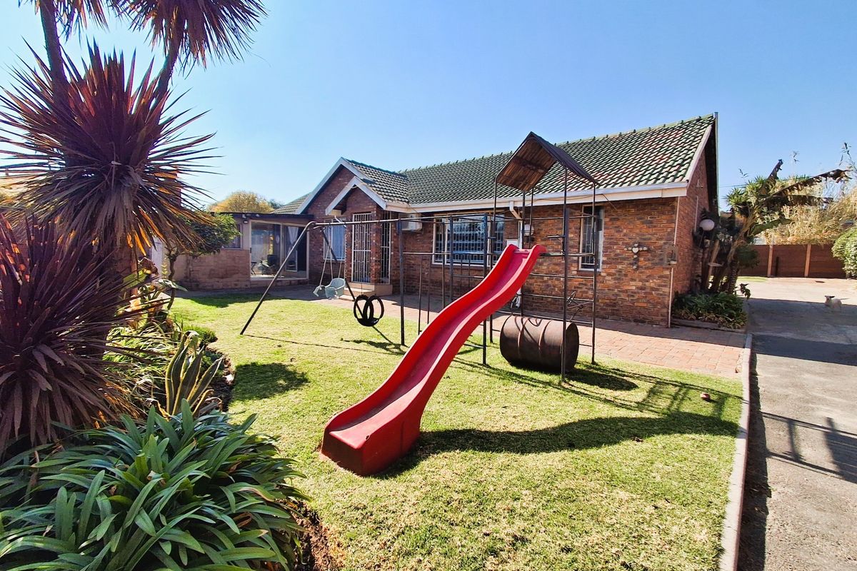 Rear view of the face brick house featuring a green tiled roof, paved pathway, and a well-maintained garden area.