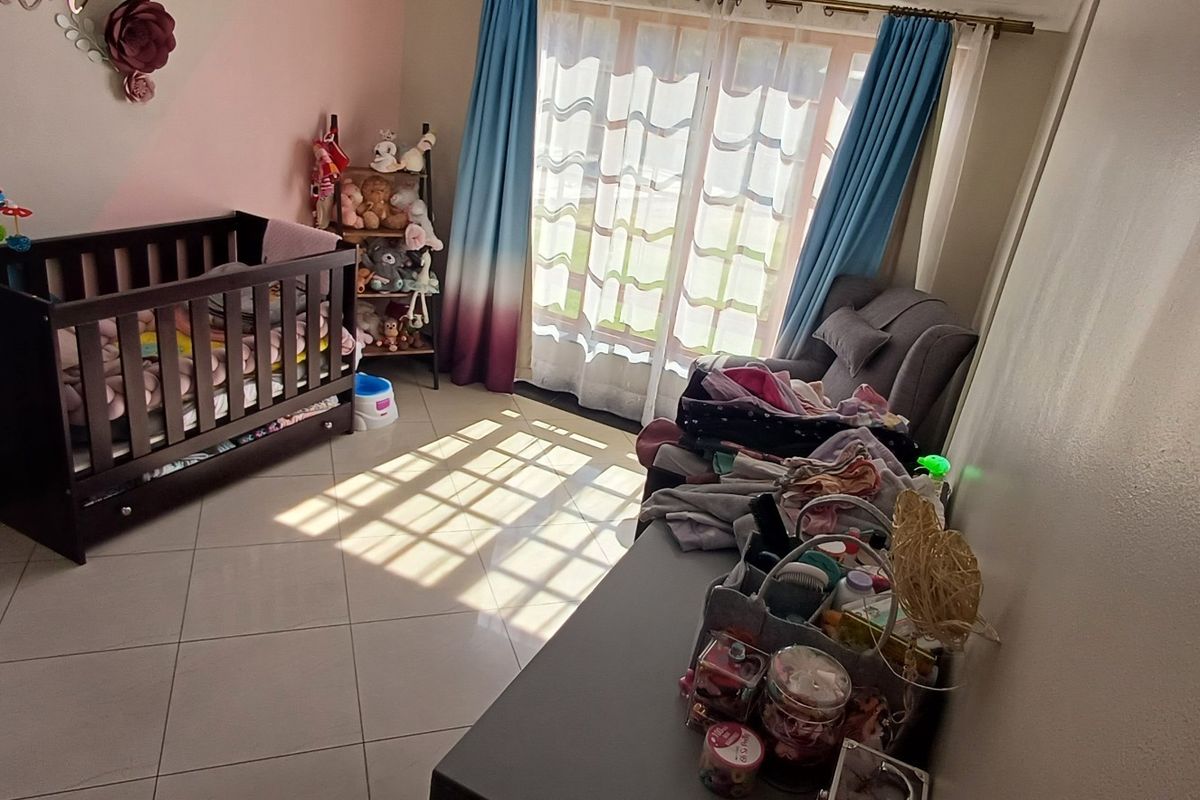 A bedroom featuring tiled flooring and a sliding glass door that provides natural light.