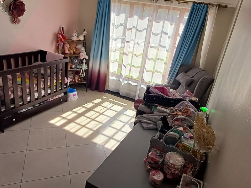 A bedroom featuring tiled flooring and a sliding glass door that provides natural light.