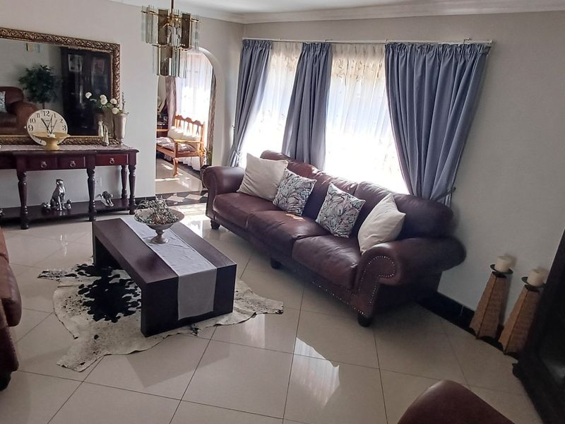 A well-maintained living room featuring polished tiled flooring, an elegant archway leading to adjacent spaces, and classic cove cornicing.