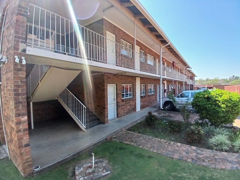Exterior view of a multi-story apartment complex featuring brick facade, external staircases, and balcony access walkways.