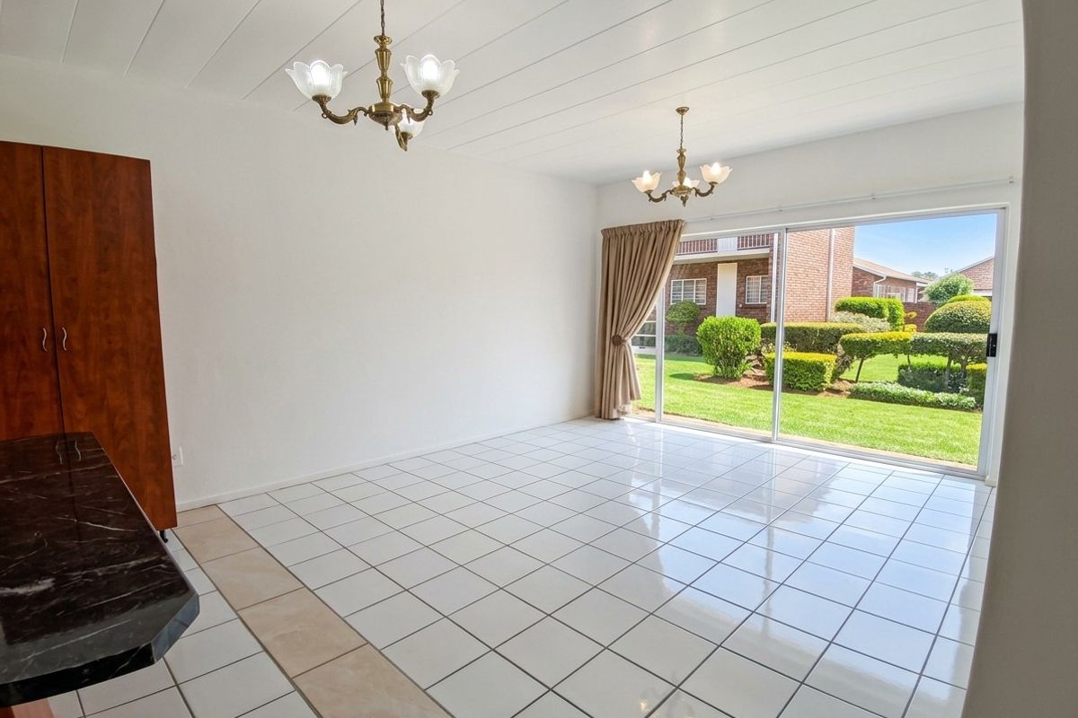 Spacious living area featuring white tiled flooring, built-in cabinetry, and large sliding glass doors providing direct access to the garden.