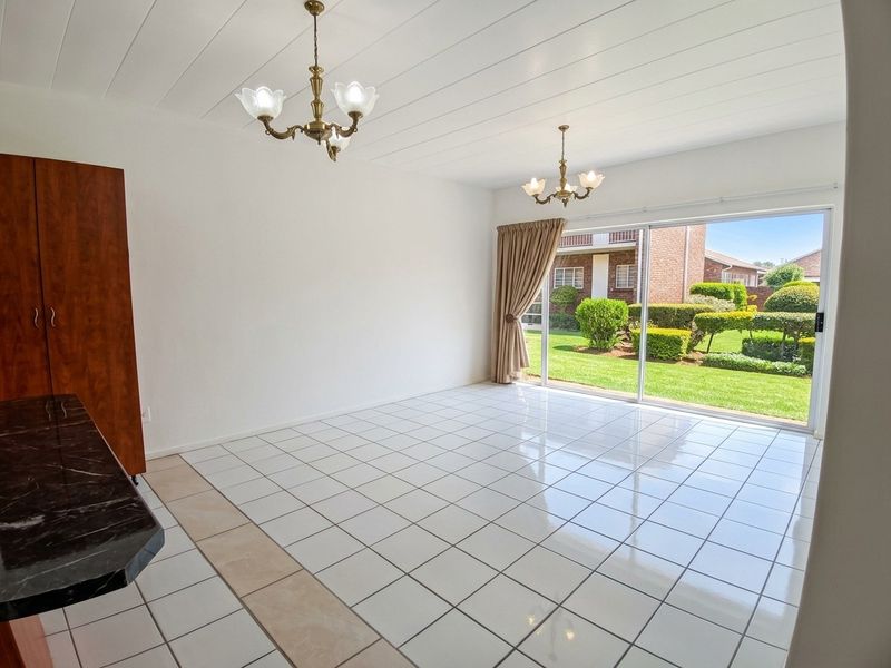 Spacious living area featuring white tiled flooring, built-in cabinetry, and large sliding glass doors providing direct access to the garden.