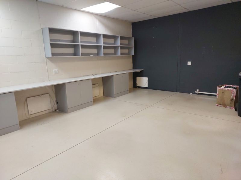 A functional office space featuring built-in desk cabinetry, wall-mounted shelving, and a clean, open layout with neutral finishes.