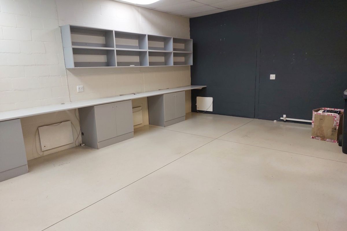 A functional office space featuring built-in desk cabinetry, wall-mounted shelving, and a clean, open layout with neutral finishes.