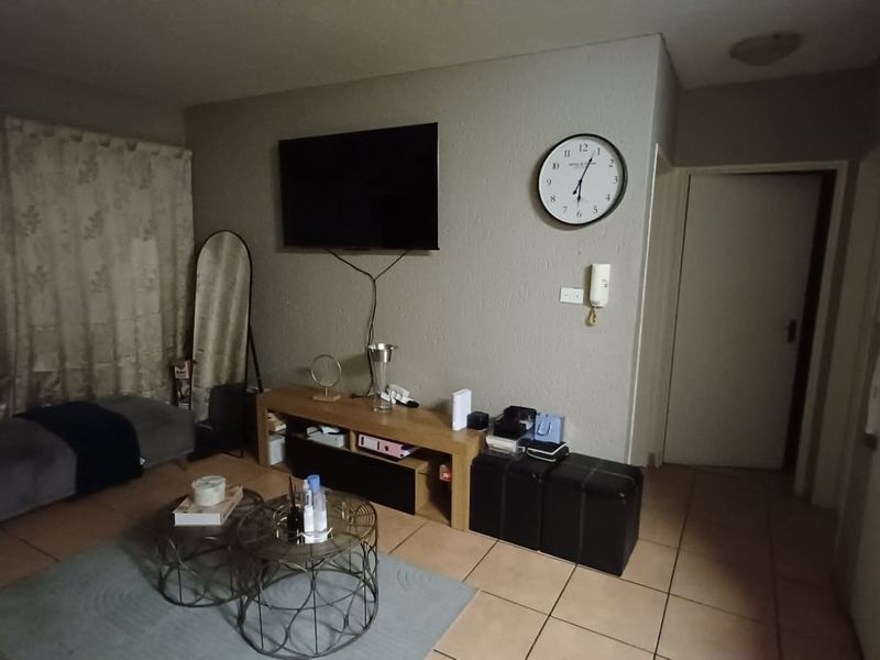 A living room area featuring tiled flooring and a wall-mounted intercom system, providing a functional space for relaxation.