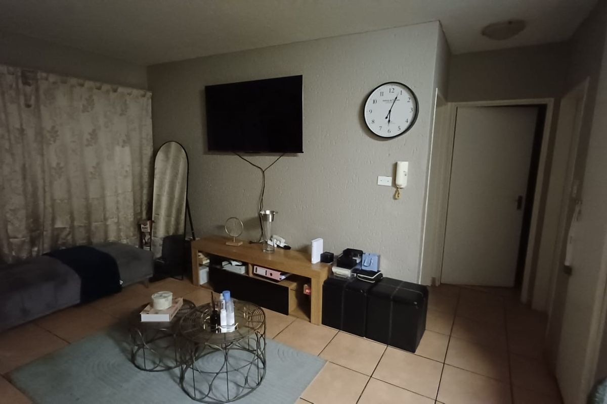A living room area featuring tiled flooring and a wall-mounted intercom system, providing a functional space for relaxation.