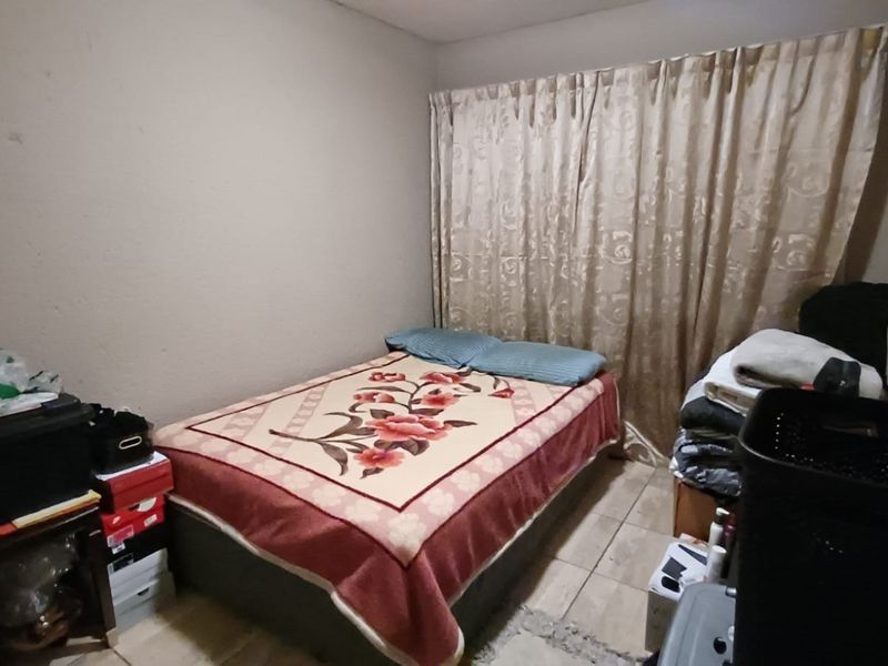 A compact bedroom featuring tiled flooring and neutral wall tones, offering a functional space ready for personalization and cosmetic updates.