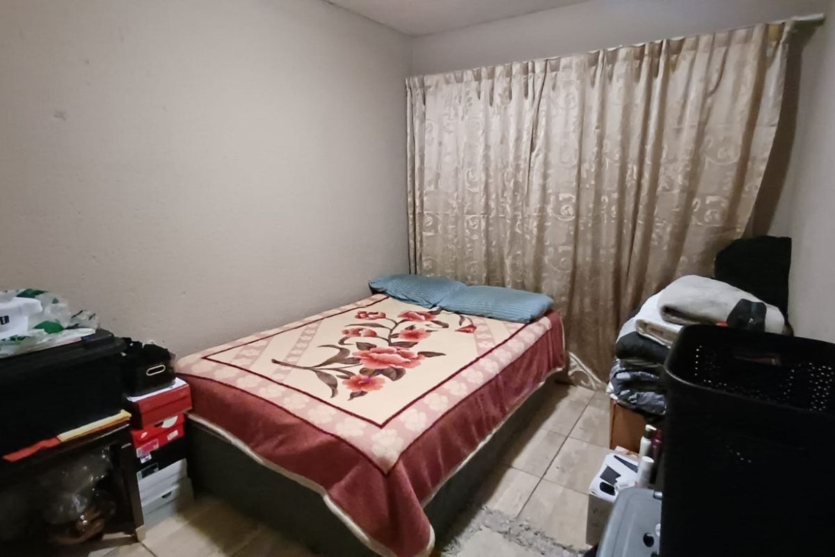 A compact bedroom featuring tiled flooring and neutral wall tones, offering a functional space ready for personalization and cosmetic updates.
