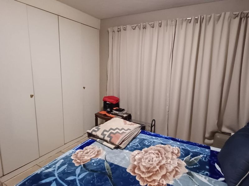 A bedroom featuring built-in cupboards and window curtains.