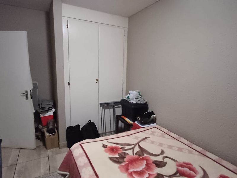 A bedroom featuring tiled flooring and a built-in wardrobe, providing functional storage space within the apartment.