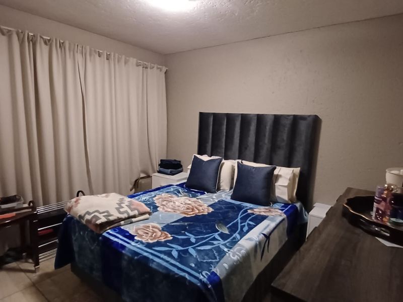 A functional bedroom featuring tiled flooring and neutral wall finishes, providing a blank canvas for potential interior updates.