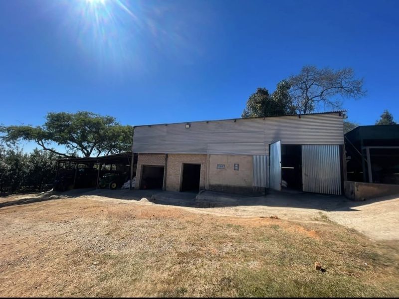 A functional farm utility building featuring corrugated metal siding, brick construction, and open-bay storage areas suitable for agricultural equipment or general farm storage.