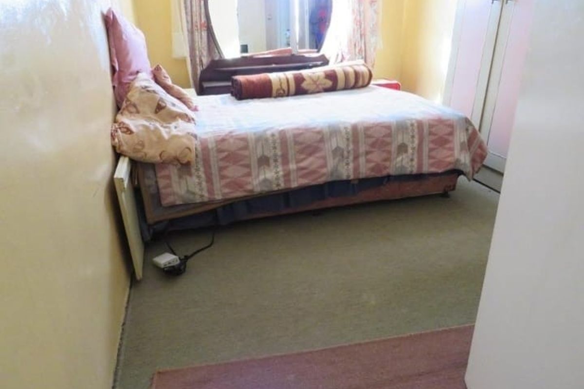 A bedroom featuring a built-in wardrobe, carpeted flooring, and painted walls in need of cosmetic updates.