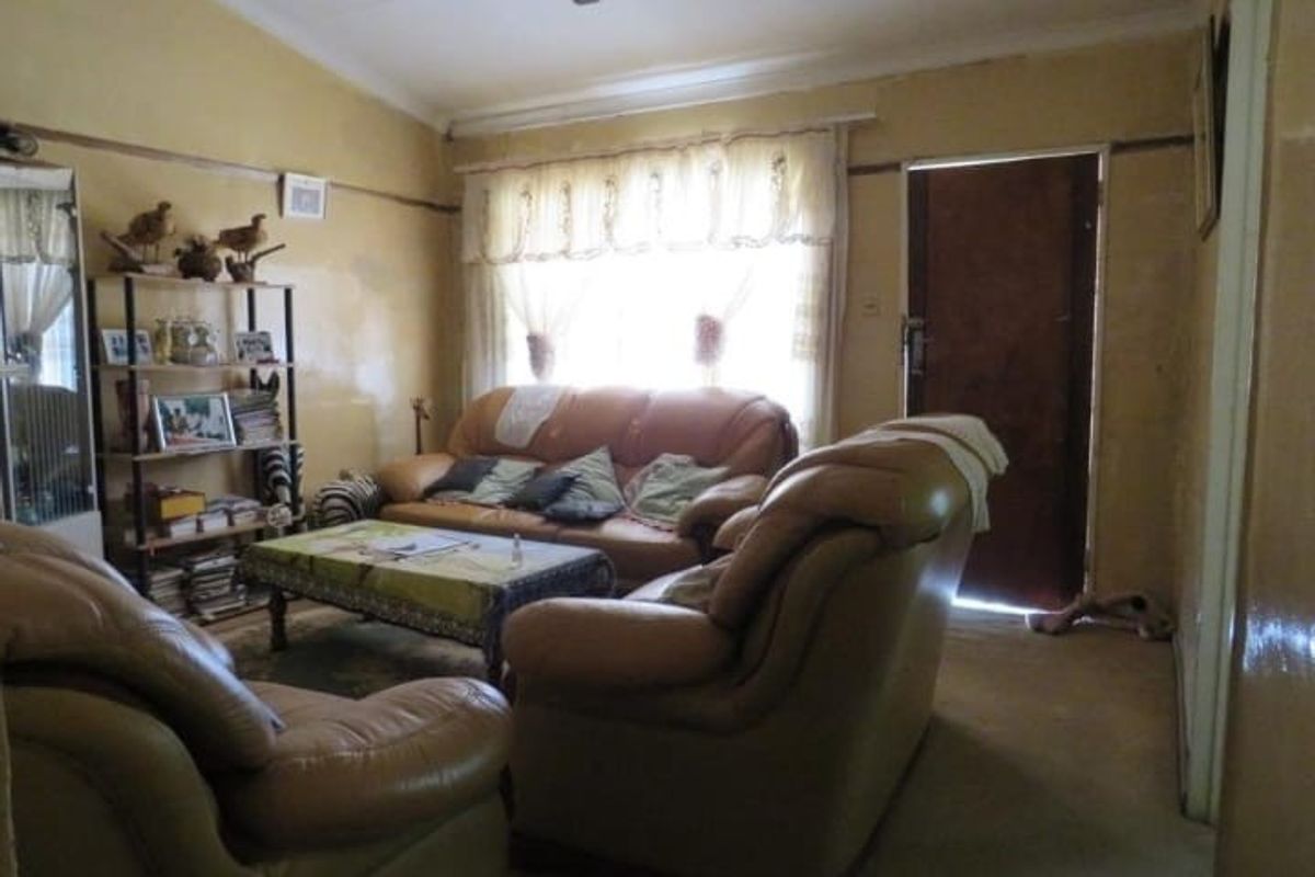 A living room featuring a ceiling fan and traditional picture rails, currently requiring cosmetic updates to the wall finishes.