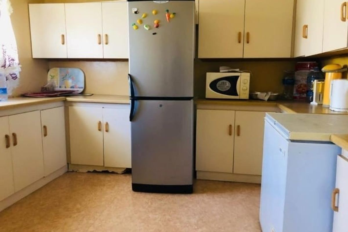 A dated kitchen featuring laminate cabinetry and countertops, providing a functional layout with built-in microwave space and ample storage.
