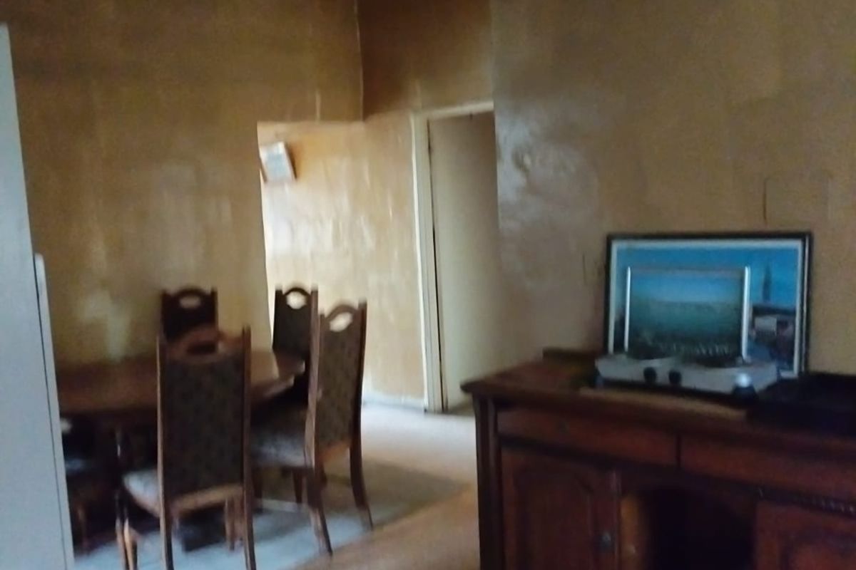 A living and dining area featuring unfinished wall surfaces and dated flooring, offering significant potential for renovation and modernization.