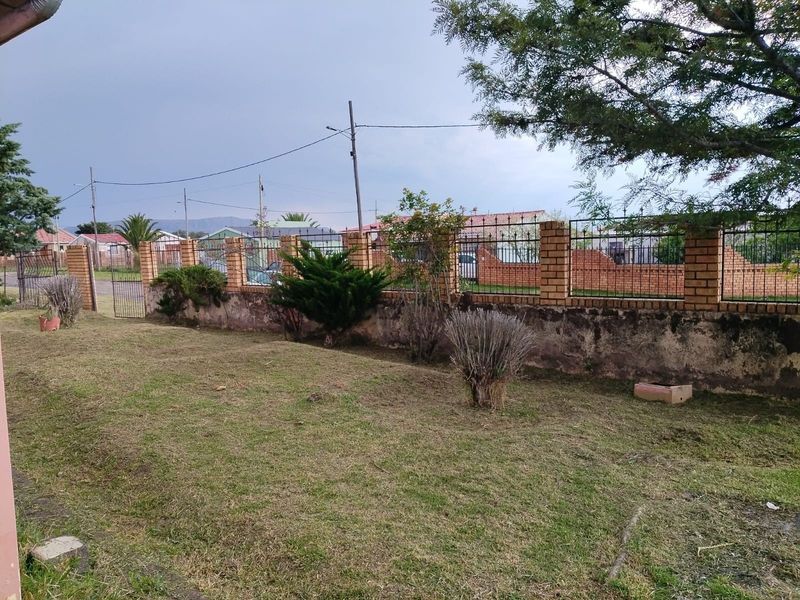 A residential garden area featuring a brick boundary wall with integrated metal security fencing and a metal gate.