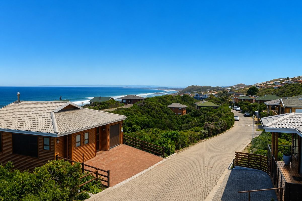 Elevated aerial view of a coastal residential street featuring timber-clad homes, paved driveways, and scenic ocean views.