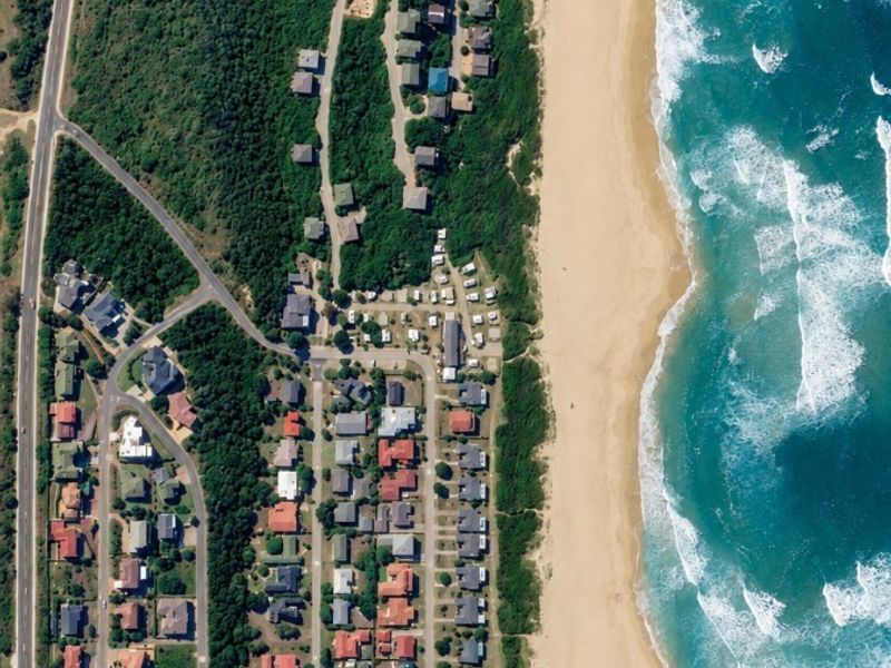 An aerial view of a coastal residential area showing the proximity of homes to the beach and local road infrastructure.