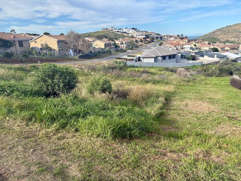 A vacant residential plot of land featuring a gentle slope, situated in an established neighborhood with surrounding residential homes.