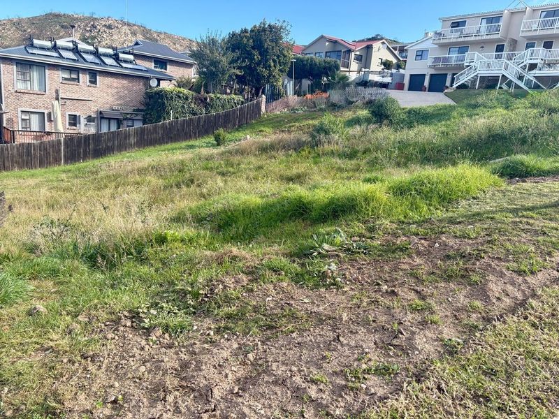 A sloped vacant residential plot situated in a developed neighborhood, offering potential for custom home construction.