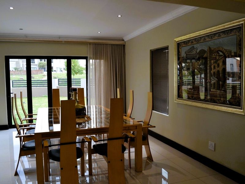 A well-maintained dining room featuring polished porcelain floor tiles, recessed downlighting, and large aluminium sliding doors providing access to the garden.