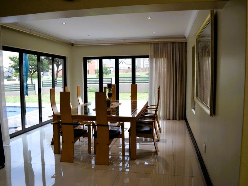Spacious dining room featuring polished tiled flooring, recessed downlighting, and large sliding glass doors providing direct access to the outdoor pool area.
