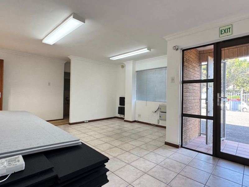 A bright, open-plan industrial entry area featuring tiled flooring, fluorescent lighting, and a secure aluminium-framed glass entrance door.