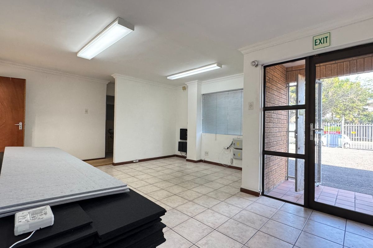 A bright, open-plan industrial entry area featuring tiled flooring, fluorescent lighting, and a secure aluminium-framed glass entrance door.