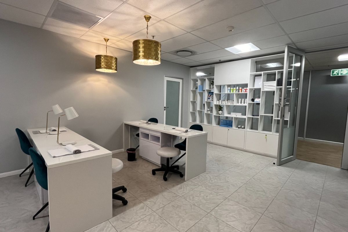 Modern professional office or salon space featuring tiled flooring, built-in display shelving, and a combination of recessed and decorative pendant lighting.