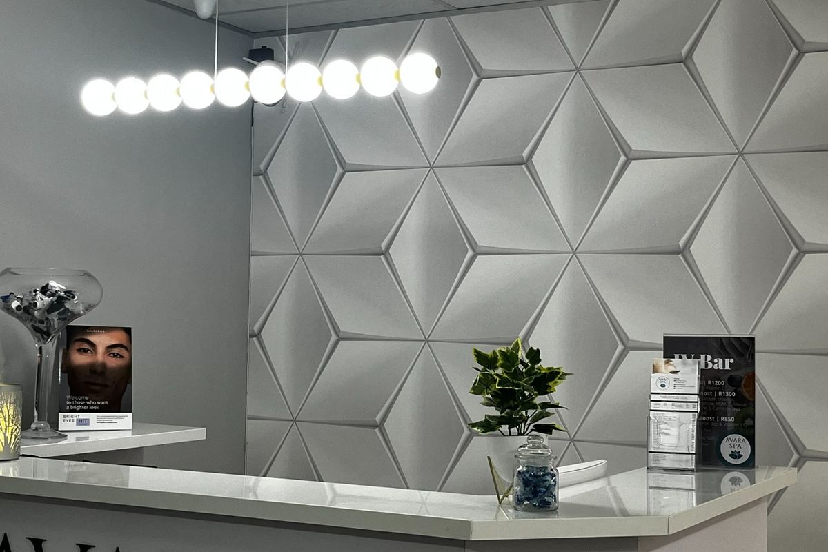 Modern reception area featuring a sleek service counter, contemporary 3D geometric wall paneling, and stylish linear pendant lighting.