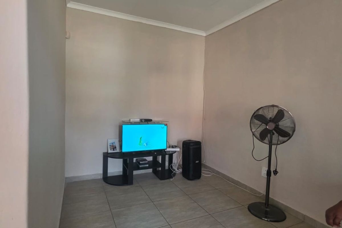 A simple living room area featuring neutral wall paint and tiled flooring, providing a blank canvas for potential interior design updates.