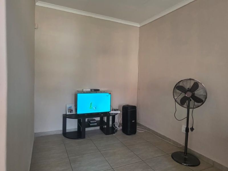 A simple living room area featuring neutral wall paint and tiled flooring, providing a blank canvas for potential interior design updates.
