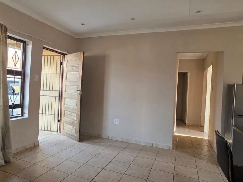 Open plan living area featuring tiled flooring, recessed lighting, and direct access to the exterior through a security gate and timber door.