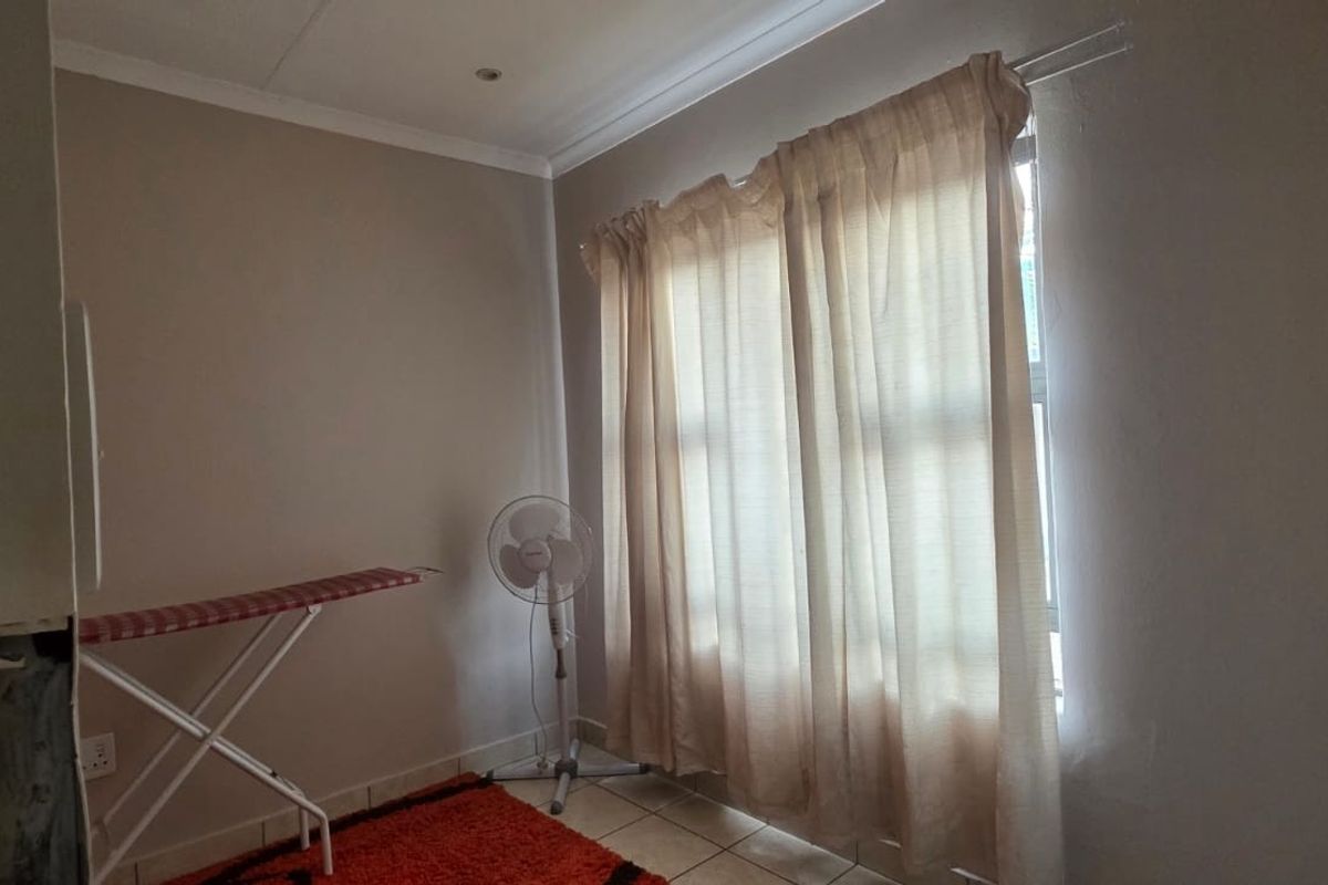 A simple bedroom space featuring tiled flooring, recessed lighting, and coved cornicing, currently awaiting final finishing touches to the wall near the entrance.
