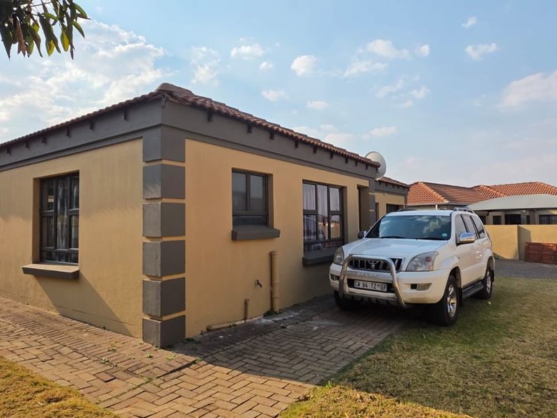 Front elevation of a single-story residential house featuring a tiled roof, paved driveway, and decorative corner quoins.