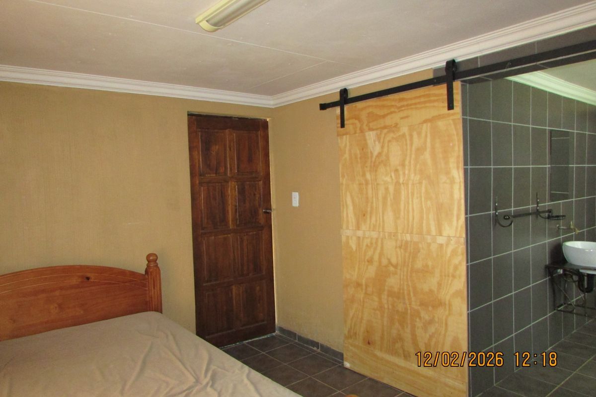 Bedroom featuring tiled flooring, a sliding plywood barn door, and direct access to an adjoining tiled bathroom area.
