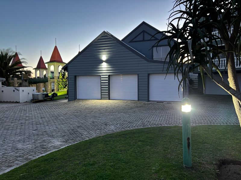 A well-maintained triple garage with paved driveway and exterior lighting, featuring modern weatherboard cladding.