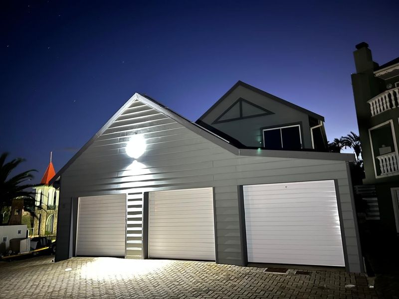 A well-maintained triple garage featuring modern weatherboard cladding and paved driveway, captured during twilight hours.