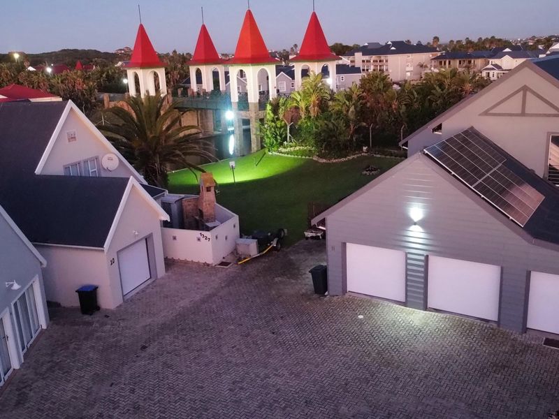 Aerial view of a residential property complex featuring multiple garages, paved driveway, and solar panel installation on the roof.
